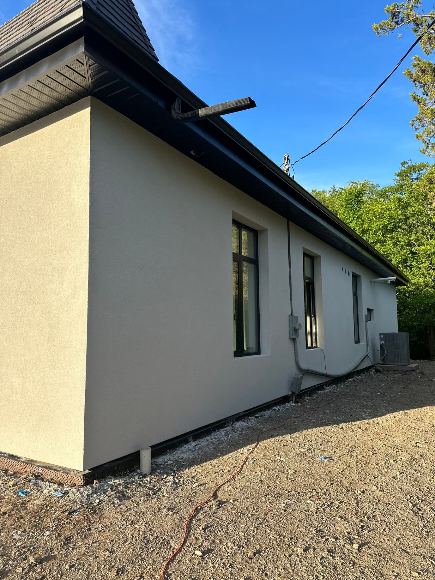 Full side elevation in warm grey stucco with square window returns