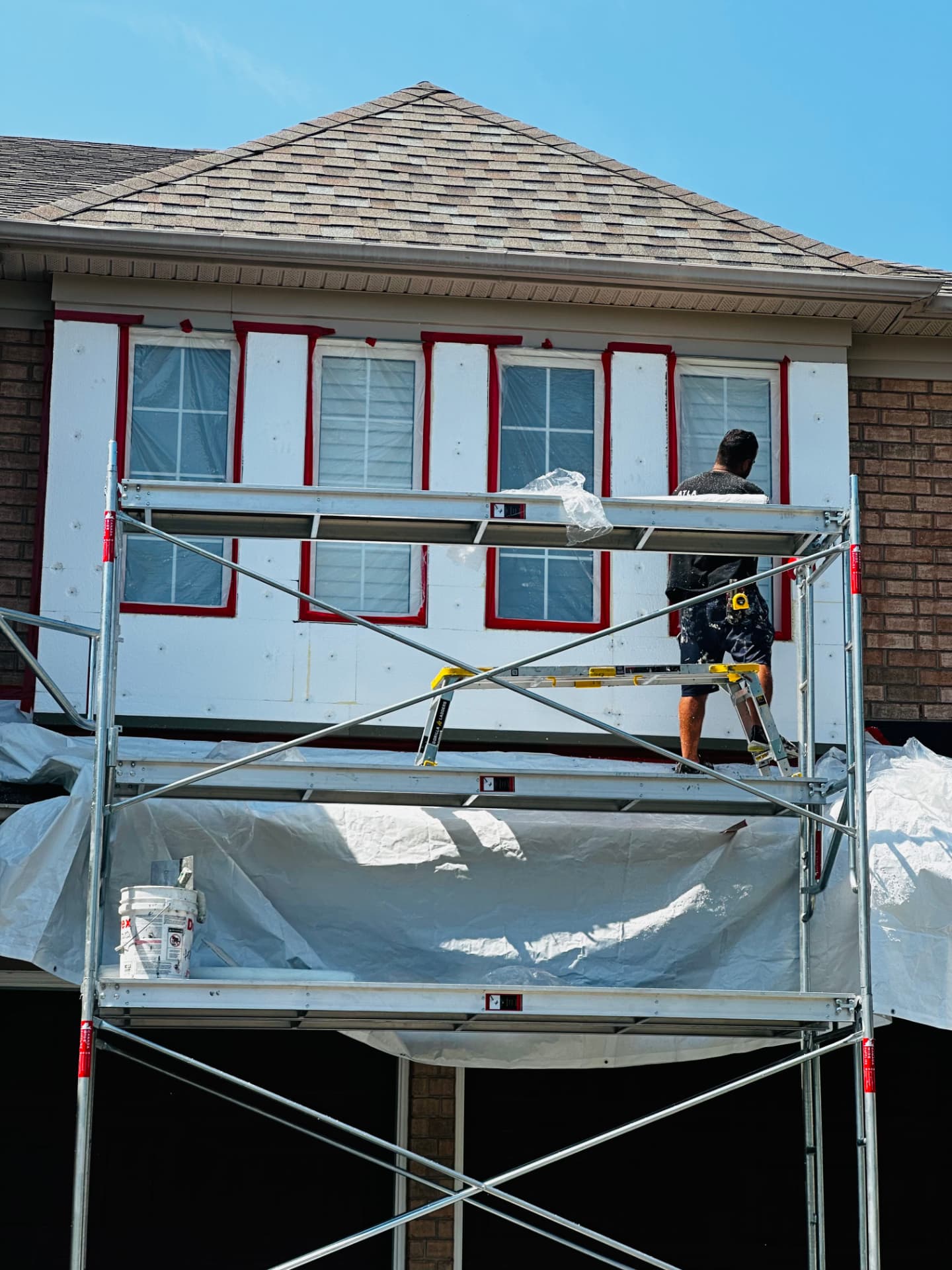 Crew member on scaffold taping windows before the base coat